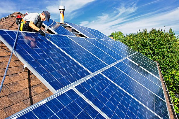 man installing alternative energy photovoltaic solar panels on roof